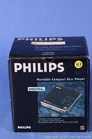 Box of Philips Portable Compact Disc Player showing model and features including rechargeable battery pack and AC adapter included.