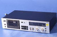 Front and top view of the Luxman K-113 stereo cassette deck with cassette compartment and control buttons visible.