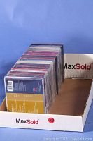 Photo showing a box with about 34 CDs arranged vertically, mostly classical music CDs in jewel cases.