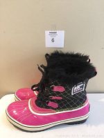 Side profile of one boot showing pink rubber lower with black quilted fabric upper and faux fur trim.