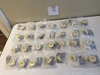 Wide view of 35 individually packaged white porcelain cabinet knobs with metal hardware laid out on a table.