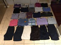 All 27 clothing items laid flat on floor showing tops and bottoms, variety of colors and styles