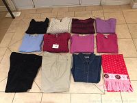 Full layout of 12 ladies plus size clothing items including tops, pants, and scarf arranged on tiled floor.