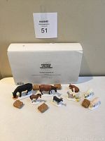 Overall view of 8 porcelain farm animal figurines and 5 hay bale replicas arranged with original Department 56 box in background.