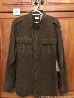 Front view of brown corduroy shirt with button front, chest pockets, and shoulder epaulets.