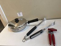 Full view of all three items together: skillet with lid, BBQ tongs, and can opener.