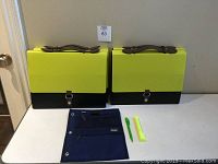 Four lime green and black file organizers with brown leather straps and snap closures, accompanied by a blue expandable file organizer and two writing instruments on a white surface.