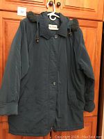 Front view of dark colored ladies plus size winter coat with hood, showing buttons, pockets, collar, and fabric texture.