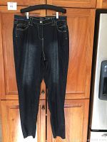 Full front view of dark blue denim jeans hanging on hanger, showing straight leg and front pockets.