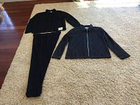 Photo showing black long sleeve button-up top with matching pants laid flat on carpet.