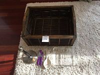 Overview of wooden basket with handles, Umbra paper towel holder, Pfaltzgraff spoon rest, can openers, and clear rectangular dish placed on a light rug.