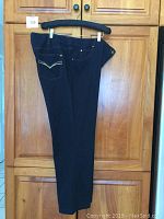 Dark blue TanJay Petites jeans hung on hanger showing front side and decorative pockets