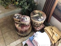 Photo showing seven decorative boxes stacked near a stair landing with floral designs featuring vases and flowers on their lids