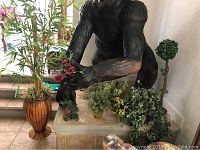 Photo showing the gorilla statue holding red flowers with various smaller plants arranged below on a ledge.