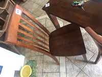 Side angle view of one wooden dining chair with vertical slats and slight scratches on seat and backrest.