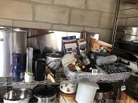 Wide view of metal stock pot, olive oil sprayer, kitchen gadgets and utensils on wire shelf