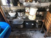 Front and angled views of metal shelving unit with kitchen and cooking items on shelves for display only