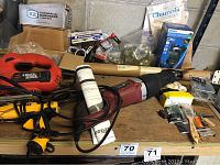 Overview of the power tools and miscellaneous hardware items on a wooden workbench in a garage.