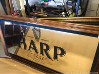 Full view of the Harp Lager branded wall mirror with wooden frame showing branding and general shape.