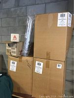 Three large cardboard boxes labeled 20 FCD Guinness with 1000 cups per box, stacked against a cinder block wall, alongside a smaller box for drink coasters and a roll of plastic gathered cups.
