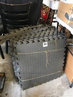 Stack of gray interlocking foam floor mats showing thickness and interlocking edges.