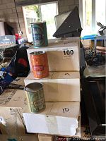 Photo showing three stacks of Deep Eddy Vodka tin can style cups in teal, orange, and green on white boxes.