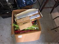 Cardboard box containing plastic translucent green and red shot glasses, a neon battery-operated shot tray, and some other items