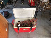 Open red and white cooler showing two black tap handles, red handles on the sides, and internal red hoses connected to beer taps.
