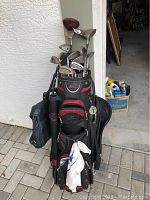 Full view of black and red Datrek golf bag filled with golf clubs and accessories, showing multiple storage compartments.
