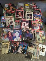 Overview of multiple vintage magazines spread out on carpet including titles Time, People, Maclean's, Woman's Weekly, and others.