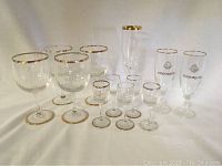 Full set of 12 stemware glasses including 4 large goblets, 4 small cordials, and 4 Codorniu champagne flutes, all with gold rims; some gold rims show age wear.