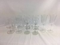 Full view of all 10 glassware pieces showing variety of shapes and sizes with clear glass and decorative etching.