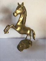 Front side view of the solid brass horse sculpture showing the rearing pose and details on the face and mane.