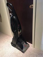 Front view of the black upright Bissell Proheat carpet cleaner with hose and power cord visible, positioned on a carpeted floor.