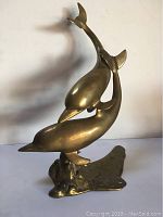 Front view of brass dolphin sculpture showing two dolphins in swimming pose.