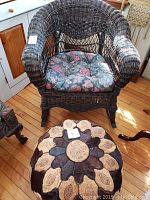 Dark brown wicker rocking chair with floral cushion seat, shown from front.