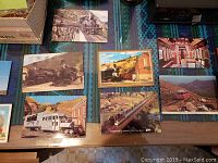 Photo showing 9 vintage postcards featuring trains, buildings, and scenic landscapes including a mule statue and train interior