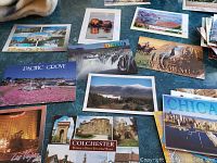 Various postcards spread out showing locations such as Pacific Grove, Colchester, Chicago, Wyoming, Idaho, and Las Vegas with scenic and landmark imagery.