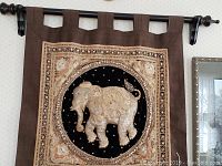 Close-up and full view of elephant wall hanging showing intricate embroidery and mounting loops on brown fabric.