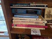 Books stacked on a wooden shelf including titles on nonprofits, accounting, literature, flowers, and quilting.