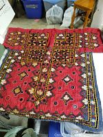 Red Pakistani dress with multicolored embroidery on a table, showing neckline and borders