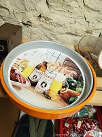 Round Coors beer tray with orange rim showing beer bottles and mugs with food.