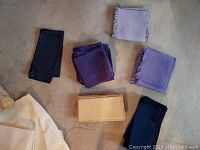 Various cloth napkins folded and laid out on carpet floor showing colors and edges