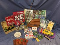 Wide shot showing the full assortment including the Doug Flutie Flakes box, trading cards, wooden chess set in box, decks of playing cards, scoreboards, and game pieces.