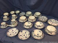 Full overview of all cups, saucers and ladle on blue cloth