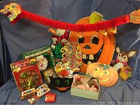 Wide shot of lot showing red and orange dragon garland banner, Santa Claus figurine, large jack-o'-lantern decoration, light-up ceramic pumpkin, animal figurine, and assorted holiday decorations.