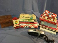 Overview of the cookbooks stacked in two piles, wooden recipe box, vintage match holder, and corded phone with coiled cord.