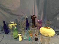 Photo showing assortment of vases of various colors, sizes and shapes against a gray background.