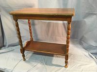 Front view of the wooden Brandt accent table showing turned legs and lower shelf.