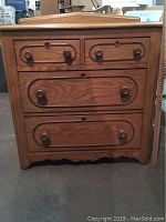 Front view of the small wooden dresser or dry sink showing four drawers with wooden knobs and keyholes.
